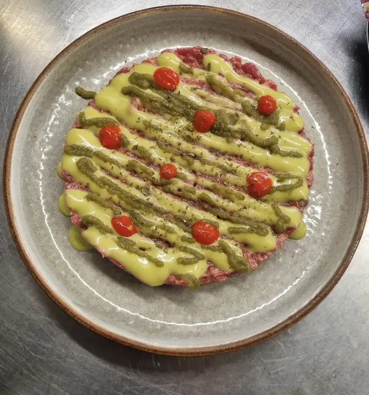 Une assiette de carpaccio, sauces jaunes et condiments sur le comptoir