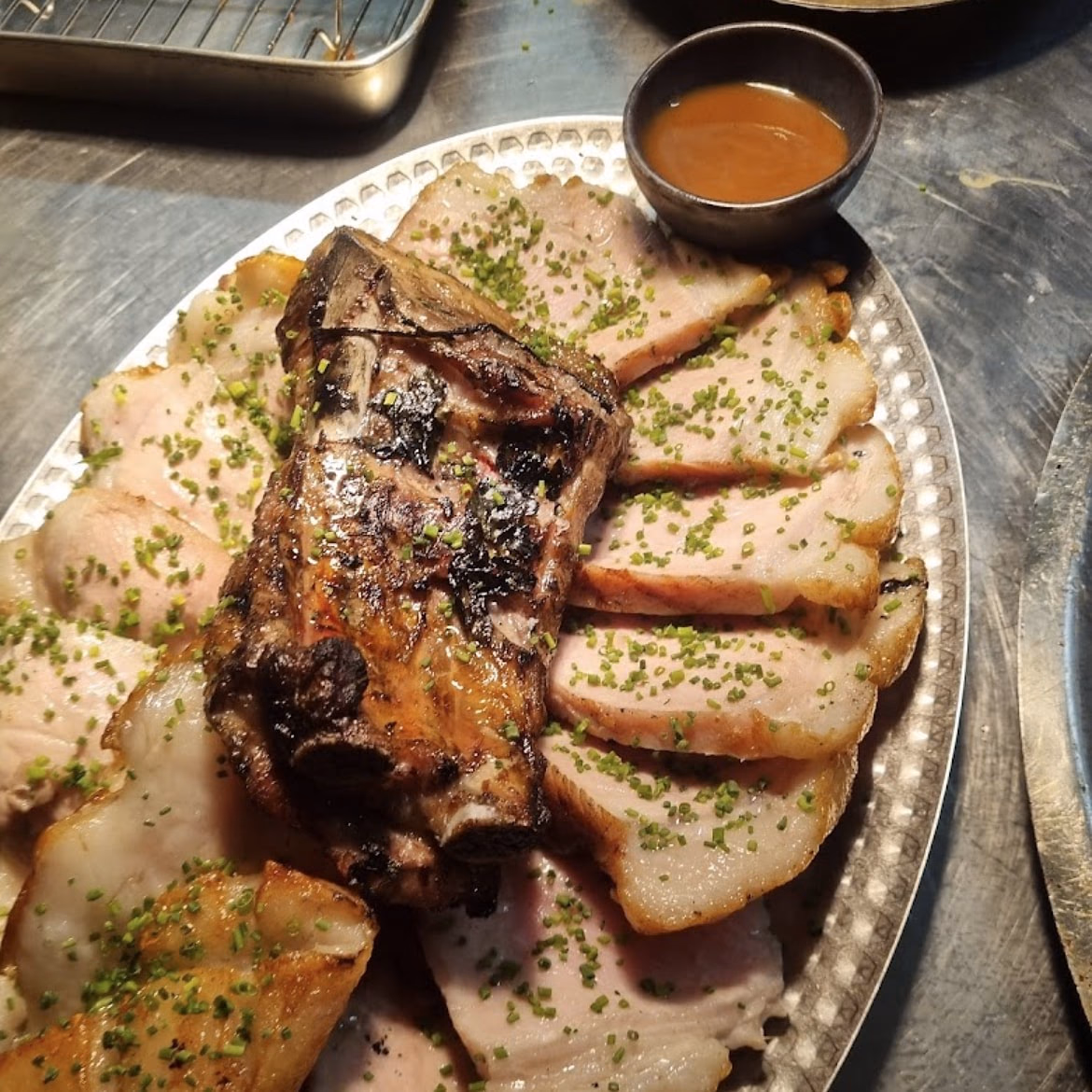 Cochon rôti tranché sur un plat martelé, ciboulette, sauce à part et frites