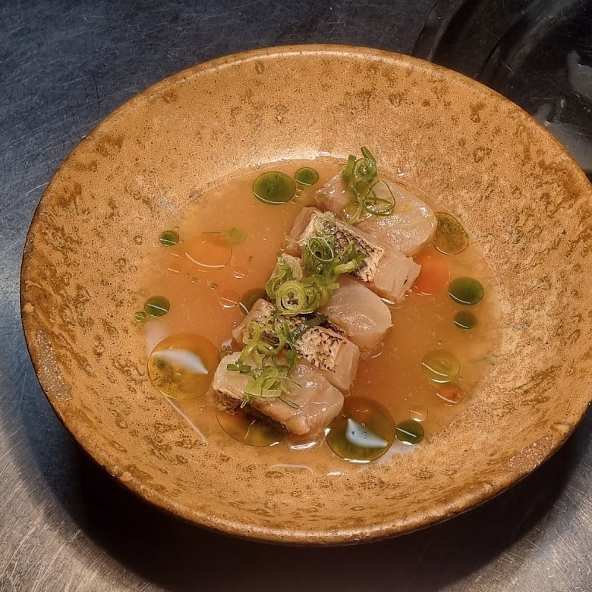Crudo de poisson blanc, oignon nouveau et huile d’herbes dans une vinaigrette de tomate, bol en grès