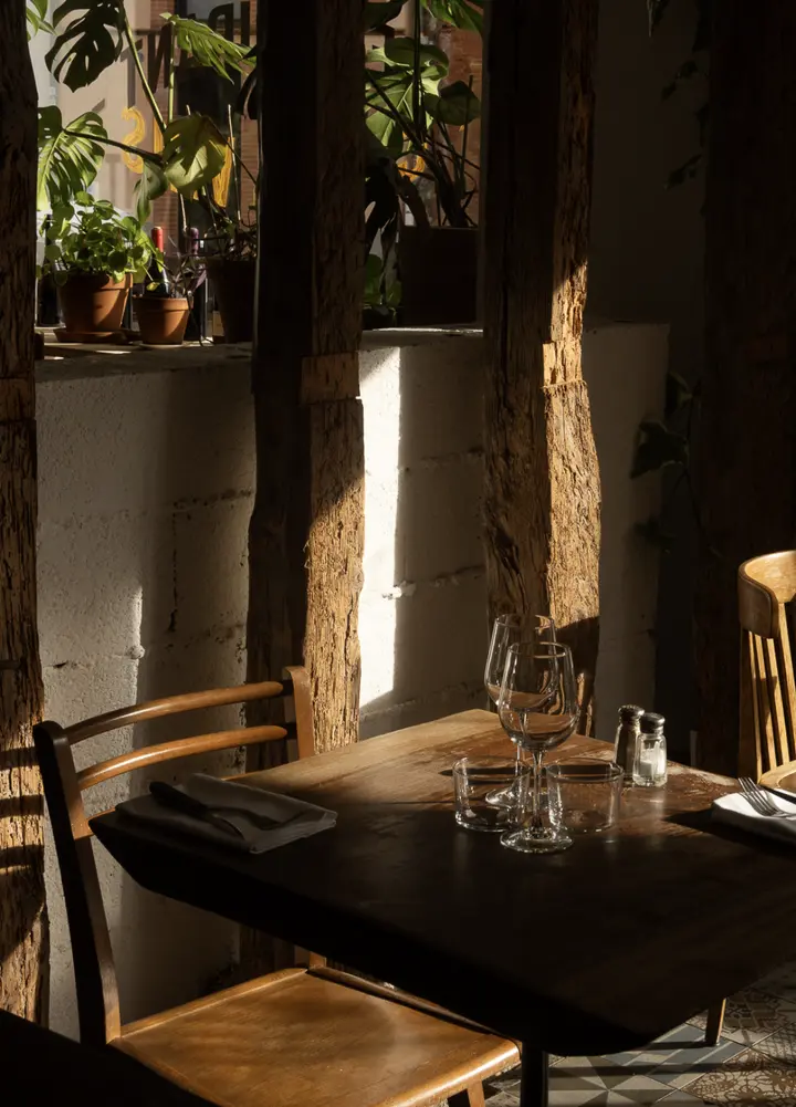Une table de Midi Minuit dans le soleil, entre les poutres et les plantes