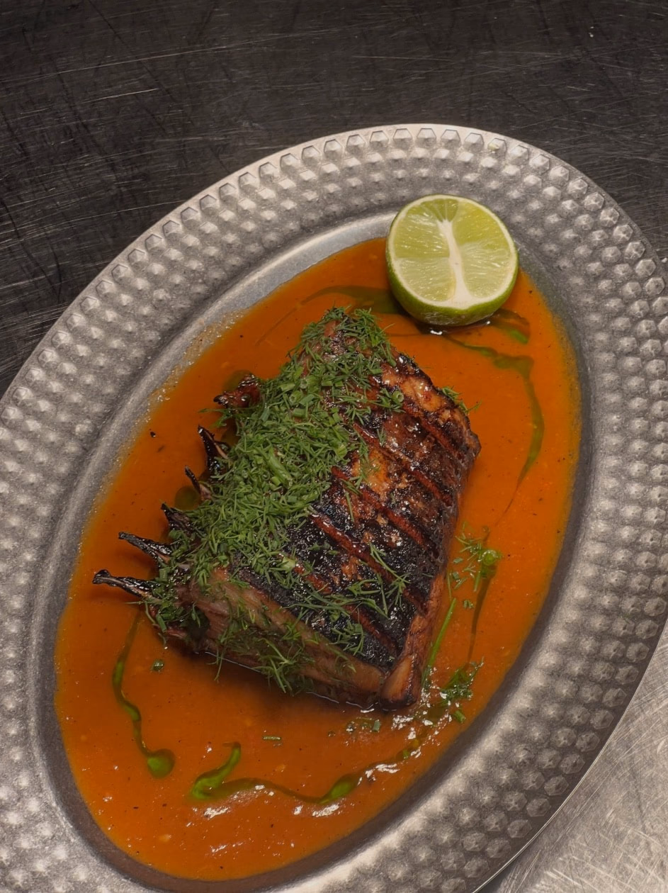 Côtelette de thon grillée sur une sauce rouge, dans un plat en métal martelé